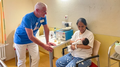 Arzt Hans-Christoph Schneider spricht in einem Zimmer auf der Kinderintensivstation Reutlingen mit einer Mutter, die ihr Frühchen im Arm hält. 