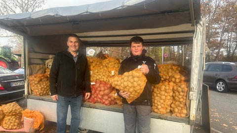 Mathias Rudolf steht mit Sohn Jonathan vor dem Anhänger voller eigener Kartoffeln. Sie verkaufen ihre Knollen auf dem Kartoffelmarkt in Reutlingen.