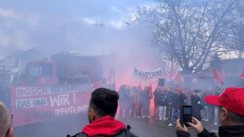 An einem Fahrzeug ist ein großes Banner befestigt. Darauf steht: "Bosch Vertrauensleute - Das sind wir!". Die Menschen protestieren gegen den geplanten Stellenabbau bei Bosch in Reutlingen.