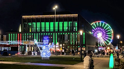 Nächtlich beleuchteter Weihnachtsmarkt mit Riesenrad um die Stadthalle in Reutlingen.