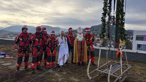 Ein Engel und ein Nikolaus mit Feuerwehrleuten auf dem Dach der Kinderklinik. Die Chefärztin hat sich nach unten abgeseilt.