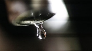 Aus einem Wasserhahn kommt ein Wassertropfen