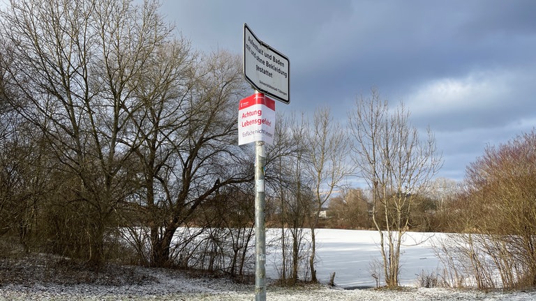 Ein Schild am Hirschauer Baggersee warnt Besucherinnen und Besucher vor dem Betreten der Eisfläche. Das sei verboten, weil es lebensgefährlich ist.