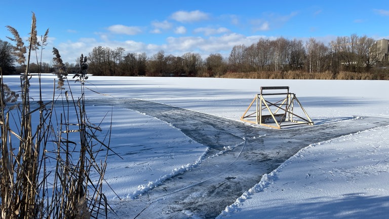 Auf dem zugefrorenen Hirschauer Baggersee stehen Eishockeytore. Teile des Schnees wurden weggeschoben. Darunter kommt die Eisfläche hervor.
