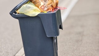 Eine überquellende Mülltonne steht am Straßenrand im Zollernalbkreis. In einigen Städten holt die Müllabfuhr die Tonnen nicht ab. 