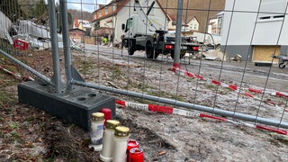 Kerzen stehen am Boden vor Trümmern des Hauses nach der Explosion mit drei Toten in Albstadt Tailfingen. Die Hilfsbereitschaft vor Ort ist groß.