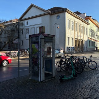Beklebte und beschmierte Telefonzelle am Straßenrand.