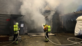 Flammen und Rauch dringen aus einer Lagerhalle. Die Feuerwehr im Einsatz bei einem Großbrand in Lichtenstein im Kreis Reutlingen.