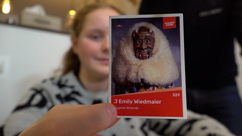 Die 14-Jährige Emily Wiedmaier aus Rottenburg hält ihren Sticker in der Hand. Darauf ist sie im Ahland-Kostüm. Die Narrenzunft hat ihr eigenes Sammelalbum
