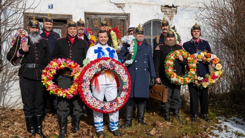 Verkleidete Schauspieler des Fasnetsspiel Burladingen vor einem alten Haus.