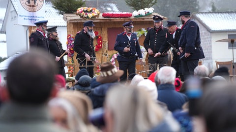 Als Feuerwehrmänner verkleidete Narren stehen auf einer Bühne beim Fasnetsspiel in Burladingen.