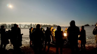 Eine Gruppe auf der hell erleuchteten, schneebedeckten Alb: Natur und Wissenswertes über die Kelten im Heidengraben bei Grabenstetten im Kreis Reutlingen. 
