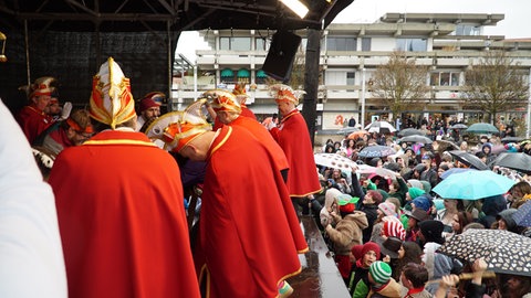 Schülerinnen und Schüler warten beim Deichelbohren in Spaichingen im Regen, während auf der Bühne gebohrt wird. 