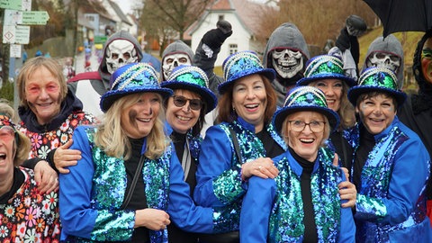 Verkleidete Menschen feiern zusammen Fasnet und haben dabei Kaminruß im Gesicht. Eine alte Tradition am Schmotzigen Donnerstag. 