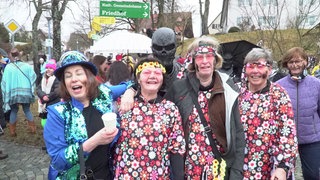 Verkleidete Menschen feiern zusammen Fasnet und haben dabei Kaminruß im Gesicht. Eine alte Tradition am Schmotzigen Donnerstag. 