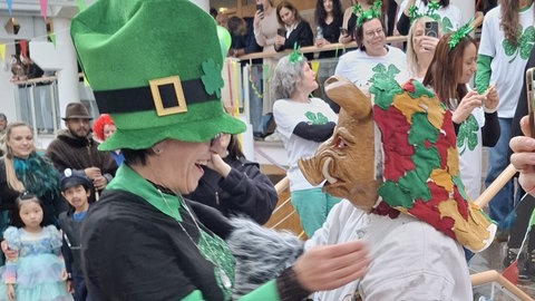 Ein Narr mit Schweinemaske steht der Metzinger Rathauschefin Carmen Haberstroh, die ein grünes St. Patrick's-Kostüm trägt, gegenüber.