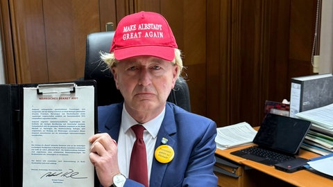 Albstadts Oberbürgermeister Tralmer (CDU) mit Trump-Perücke und rote Kappe mit der Aufschrift "Make Albstadt Great Again".