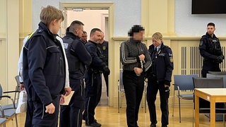Vollstreckungsbeamte führen einen Angeklagten in den Gerichtssaal. Nach dem Urteil im Hechinger Entführungsprozess wird gegen den Vater von zwei Verurteilten ermittelt (Archivbild)