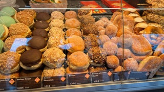 In einer Auslage liegen verschiedene Berliner und Fasnetsküchle. Das süßge Gebäck gibt es in Tübingen auch noch Tage nach der Fasnet.