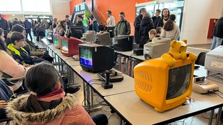 Jugendliche und junge Erwachsene sitzen vor einem alten Computer. Sie zocken Videospiele aus den 1980ern. Die Retro Games Con in Balingen macht das möglich.