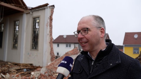 Pfarrer Johannes Hartmann steht vor der Kirche in Tailfingen, die schon teilweise abgerissen ist.