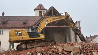 Ein Bagger steht vor dem Kirchenschiff der Erlöserkirche in Tailfingen. Bereit zum Abriss.