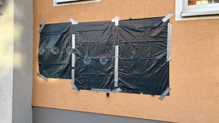 Mit Plastik überklebte Schmierereien an einer Hauswand in Betzingen