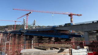 Brückenbau mit Kränen und Gerüsten über einem dem Neckartal.