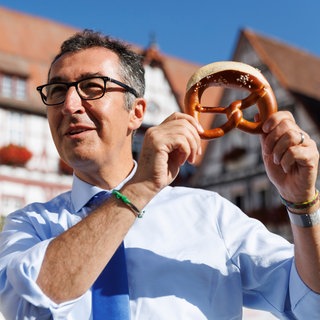 Cem Özdemir, Bündnis 90Die Grünen, steht auf dem Marktplatz in Bad Urach und hält eine Brezel in den Händen. Er wird voraussichtlich neuer Ministerpräsident in Baden-Württemberg.