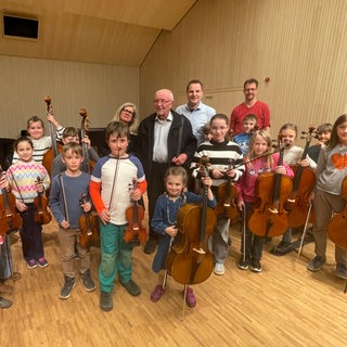 Manfred Schrader steht zwischen den Kindern des Liedorchesters der Musikschule Tübingen. In Zukunft sollen hier Kinder aus sozialschwachen Familien ein Stipendium erhalten. 