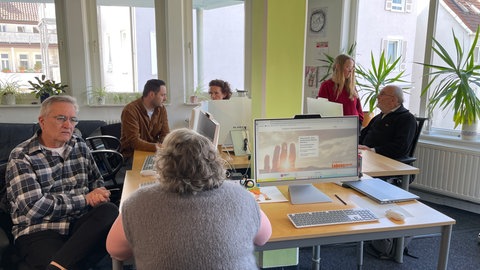 Ehrenamtliche vom "Arbeitskreis Leben ReutlingenTübingen" sitzen an Tischen. Sie beraten Menschen in Lebenskrisen.
