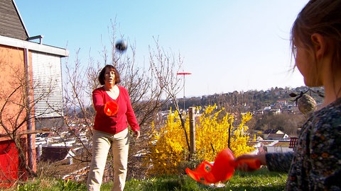 Rentnerin Ursula Müller spielt mit ihrem siebenjährigen Patenkind ein Ballspiel im Garten