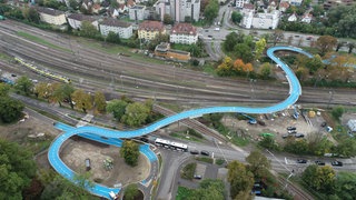 Die blaue "Ann Arbor"-Fahrradbrücke aus der Luft. Sie schlängelt sich über die Bahnschienen. Unbekannte haben ein Loch in die Brücke gefräst.
