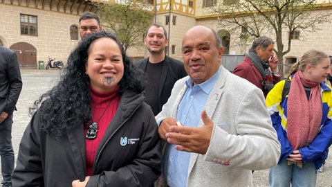Zwei Mitglieder der Maori-Delegation stehen lächelnd im Tübinger Schlosshof. Sie freuen sich über die Heimreise des Ahnenbildes.