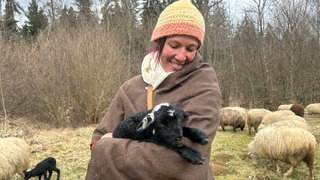 Tierpflegerin Mali vom Campus Galli hält ein kleines Lamm im Arm. Die Freilichtmuseen der Region starten in die Saison.