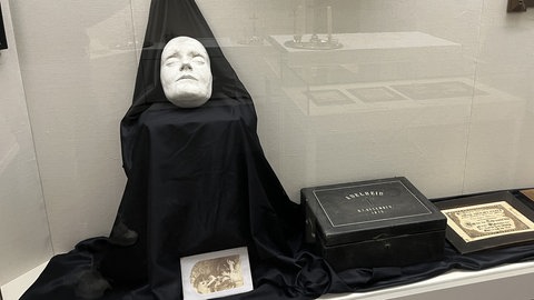 Eine Totenmaske aus Gips liegt auf einem schwarzen Tuch. Sie wird im Museum für Volkskunst in Meßstetten ausgestellt.