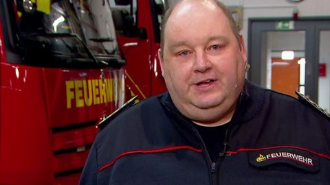 Albstadts Stadtbrandmeister Thomas Daus steht in einem Feuerwehrgebäude vor Einsatzfahrzeugen.