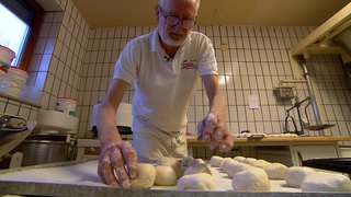 Bäckermeister Gerold Rebholz formt Brötchen. Er hat 60 Jahre lang Erfahrung und will trotz seines Alters von 74 Jahren noch nicht aufhören.