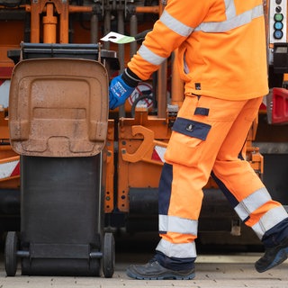 Eine braune Biomülltonne wird von einem Mitarbeiter geleert. In Tübingen haben Müllmänner Biomüll jahrelang in einer Restmülltonne eingesammelt. Jetzt will die Stadt Schadensersatz zahlen.