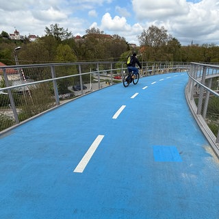 Der Belag auf der beheizten Fahrradbrücke in Tübingen wurde repariert. Zu erkennen ist die reparierte Stelle an einem Rechteck in hellerem Blau, verglichen mit dem Rest der Fahrbahn.