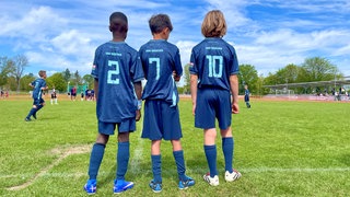 Drei Spieler der U10 Jugendmannschaft von 1860 München stehen am Spielfeldrand und warten auf ihren Einsatz. Der Bentley-Cup ist ein hochkarätig besetztes U10 Jugendfußball Turnier mit Mannschaften aus Europa.