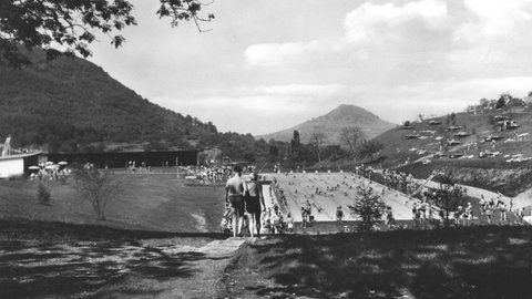 Historische Schwarz-Weiß-Aufnahme vom Waldfreibad Eningen. Totale aus leicht erhöhter Position. Zwei Personen im Vordergrund.