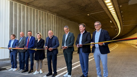 Vertreter von Bund, Land und der Stadt Albstadt schneiden gemeinsam ein Flatterband am Tunnel in Albstadt-Laufen durch. Die Sanierung ist abgeschlossen, der Tunnel aber noch nicht freigegeben.