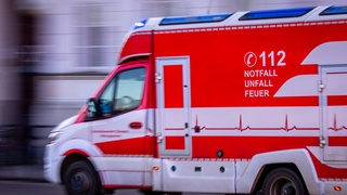 Ein Krankenwagen fährt mit Blaulicht auf einer Straße