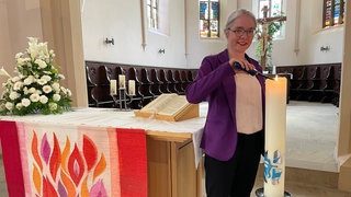 Die Pfarrerin Christine Siegl zündet vor der Sakristei in der evangelische Peter und Paul Kirche in Gönningen eine Kerze an.