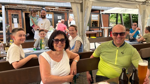 Eine Familie sitze auf der Terrasse des Wanderheims "Die Hütte" auf der "Eninger Weide".