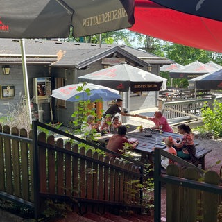 In einem Biergarten sitzen sieben Leute um einen Tisch herum und werden bedient. In der Kirchbühlhütte in Mahlstetten kann man sich auch an heißen Tagen erfrischen.