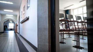 Symbolbild: Ein leerer Schulflur. Durch eine geöffnete Türe sieht man ein Klassenzimmer, in dem aufgestuhlt wurde. Nachdem einem Lehrer sexualisierte Übergriffe vorgeworfen wurden, unterrichtet er nicht am Progymnasium Rosenfeld.