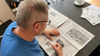 Michael Kaltenmark aus Rottenburg sitzt Zeitung lesend am Esstisch. Mit Anfang 30 hatte er einen Schlaganfall. Seitdem leidet er an einer Sprachstörung, einer Aphasie. 