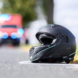 Ein Motorradhelm liegt auf einer Straße, im Hintergrund ist ein Krankenwagen zu sehen. Am Wochenende haben mehrere Motorradunfälle zwischen Neckaralb und Nordschwarzwald ereignet. 